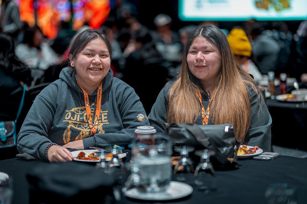 Two young women friends smiling together at conference table with food