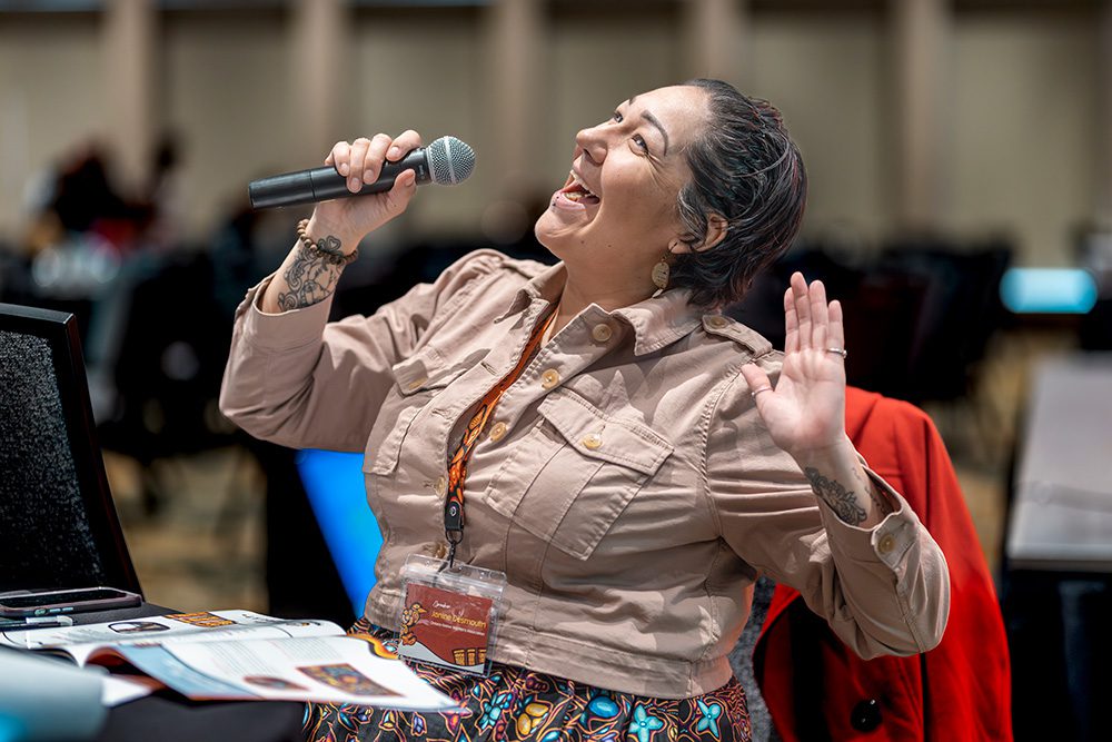 Woman delivering energetic presentation or performance with microphone at conference