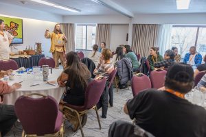 Guest speaker in traditional clothing presenting to seated conference attendees