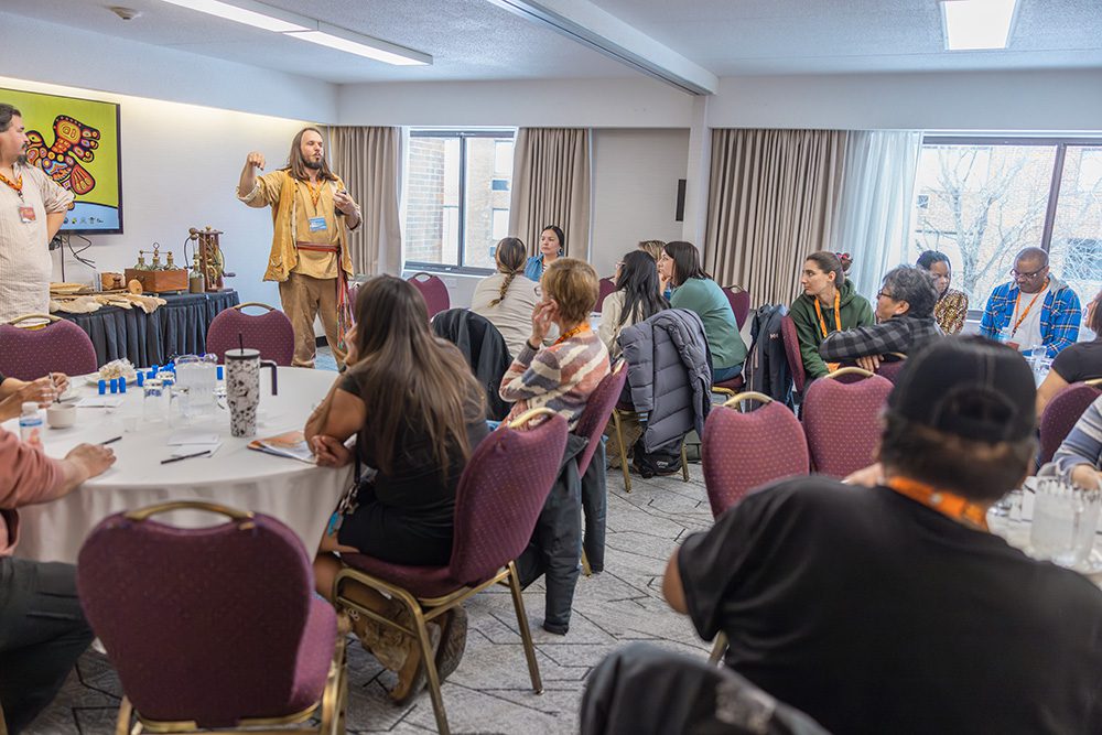 Guest speaker in traditional clothing presenting to seated conference attendees