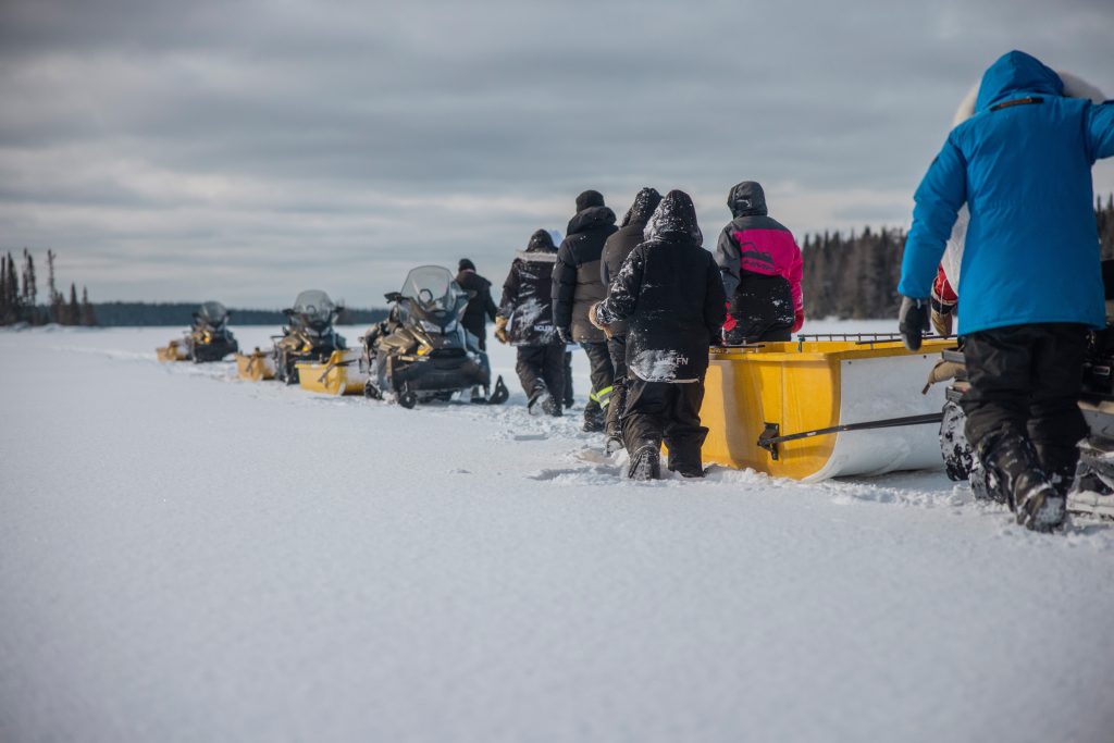 tudents and educators working together pulling sleds during winter survival trip