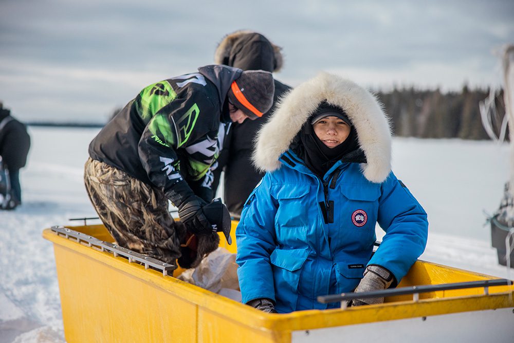 Young student in yellow sled during winter survival camping trip preparation