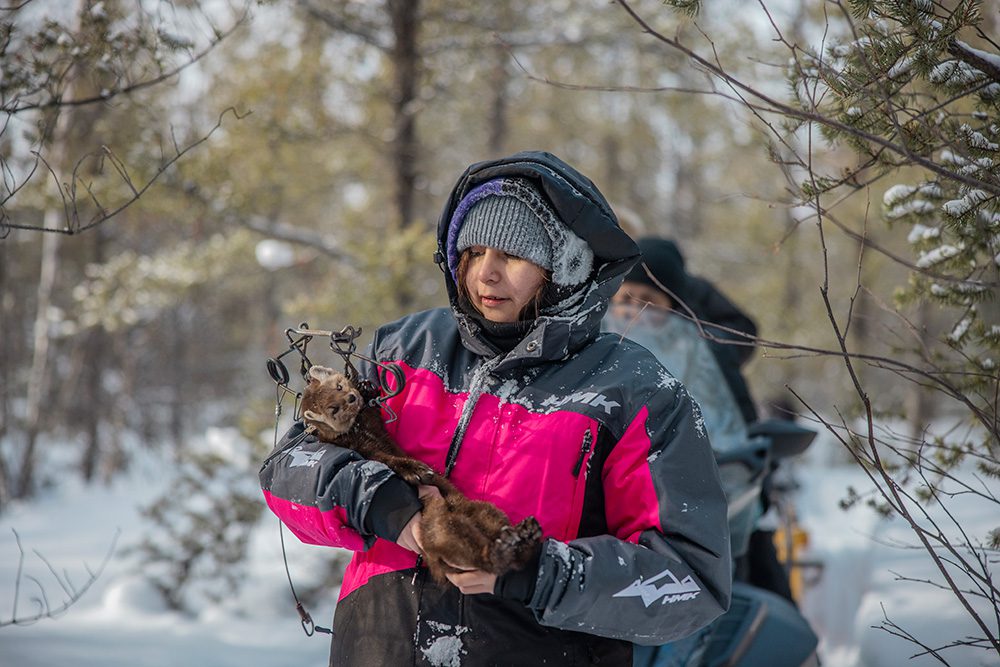 Youth holding trapped animal learning traditional trapping methods winter camping