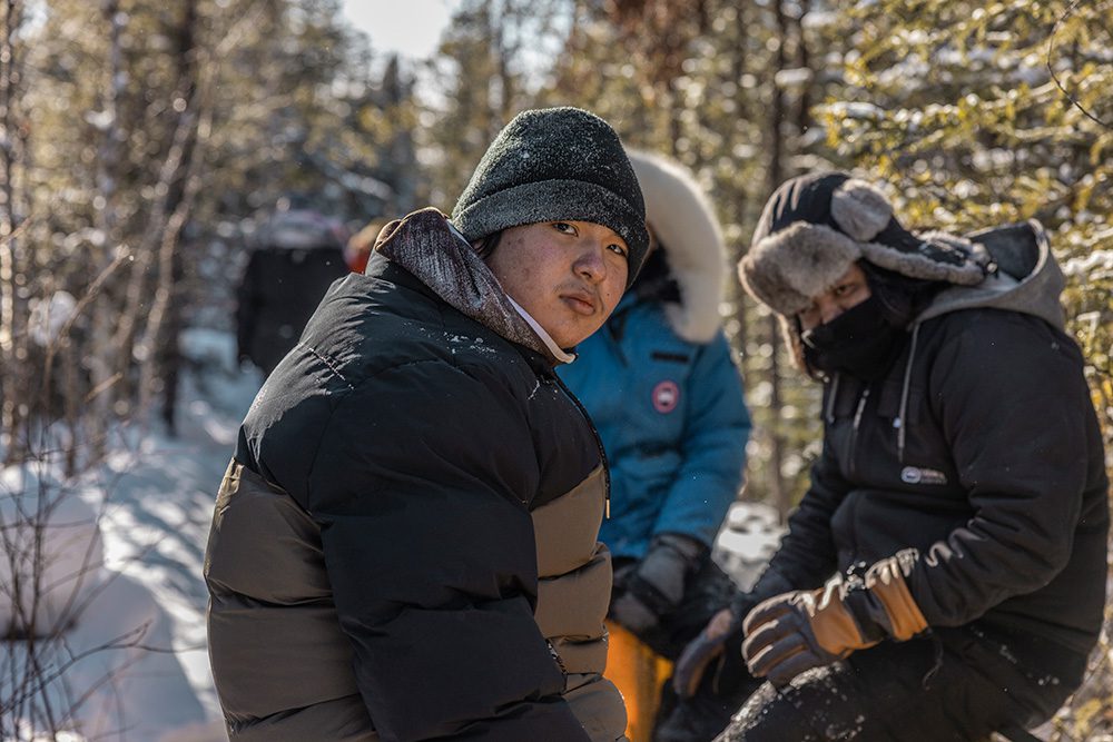 Elder teaching youth winter survival and trapping skills during remote camping trip