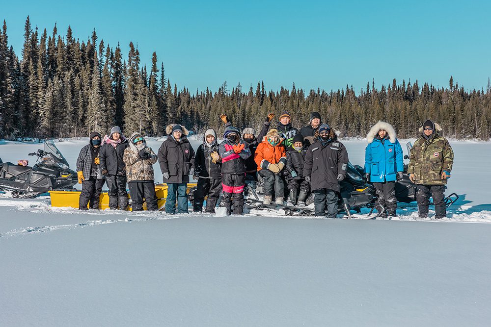 High school students and educators gathered on frozen lake during winter survival camping trip North Caribou Lake