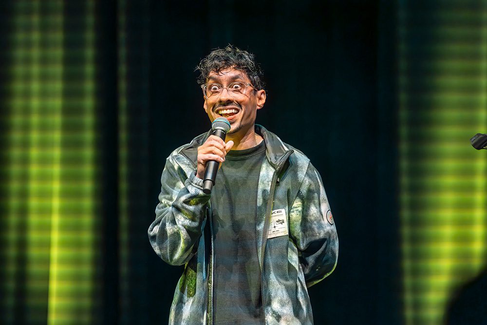 Comedian with exaggerated facial expression performing stand-up with microphone