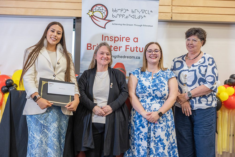 Student receiving graduation certificate with educators at Thunder Bay ceremony