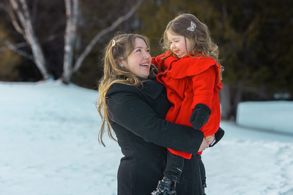 Mother holding daughter close during warm winter family photography moment
