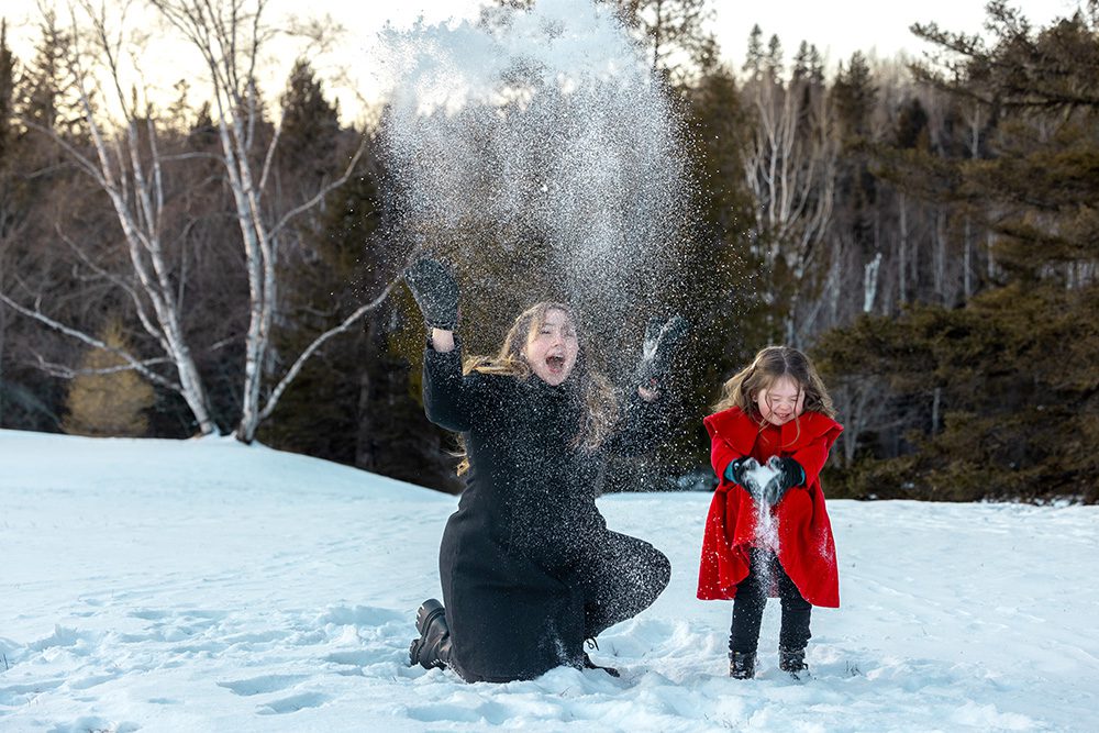 Mother and daughter throwing snow together during playful winter photography session