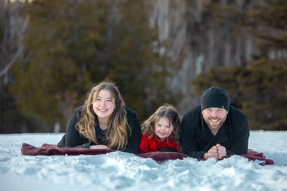 Child laughing with parents on blanket during comfortable winter family photography