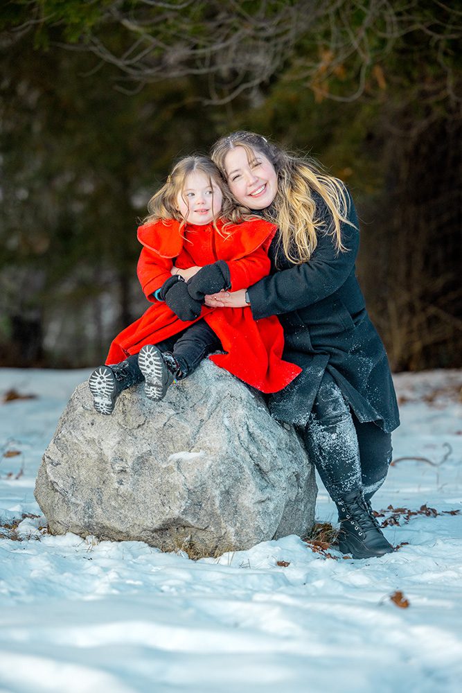 Mother and daughter sharing special moment on rock during winter family photography
