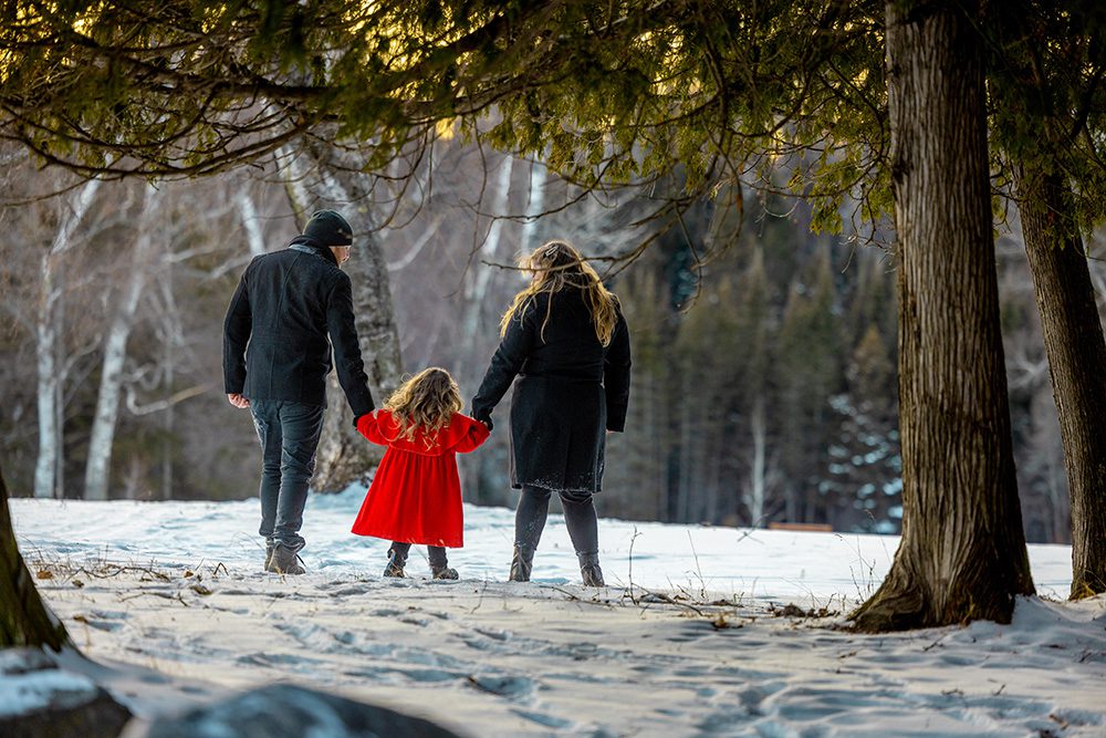 Family walking together into forest during adventurous winter family photography session