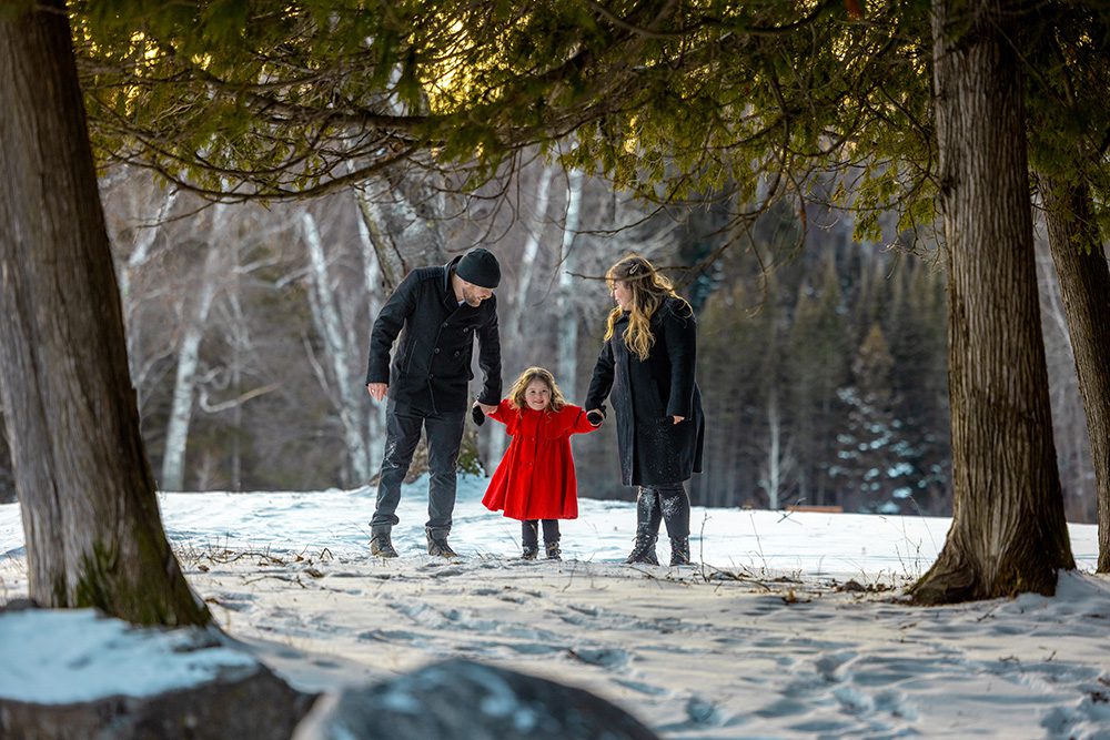 Child walking between parents through snow during active winter family photography session
