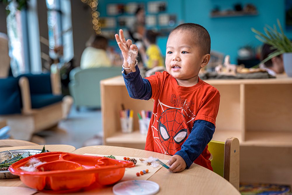 Toddler in Spider-Man shirt waving at camera during community program