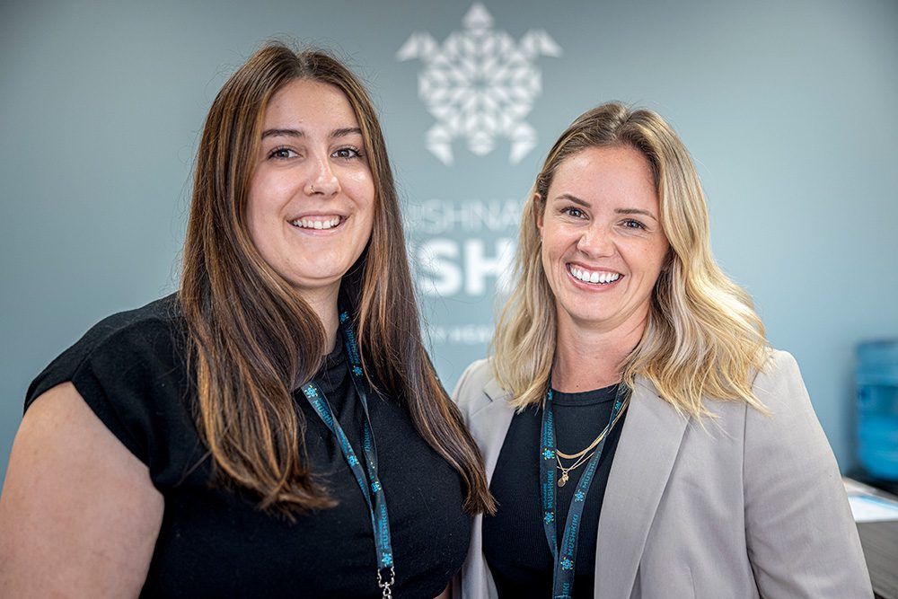 Two female healthcare staff members smiling in professional attire at Anishnawbe Mushkiki