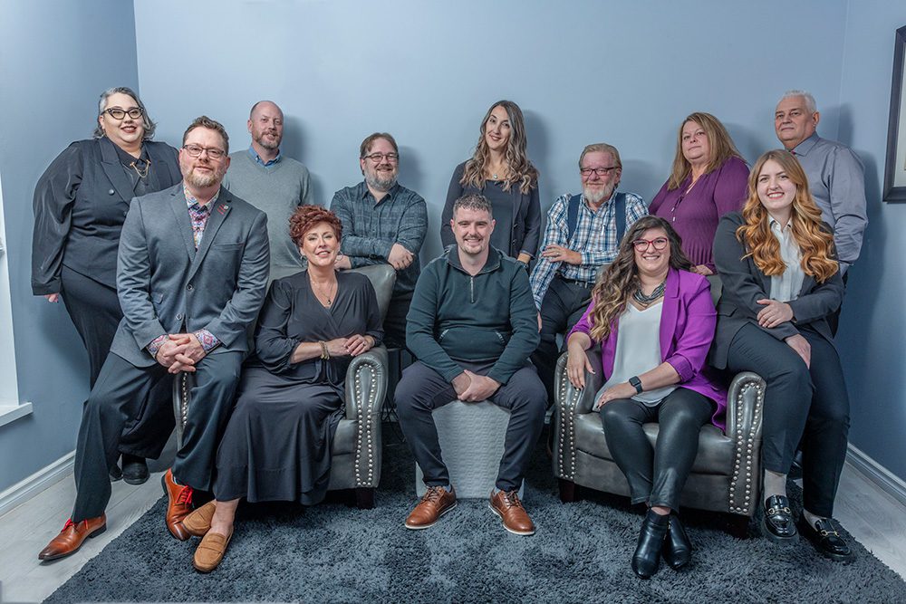 Professional team photo of Titan Transline staff in business attire against blue backdrop