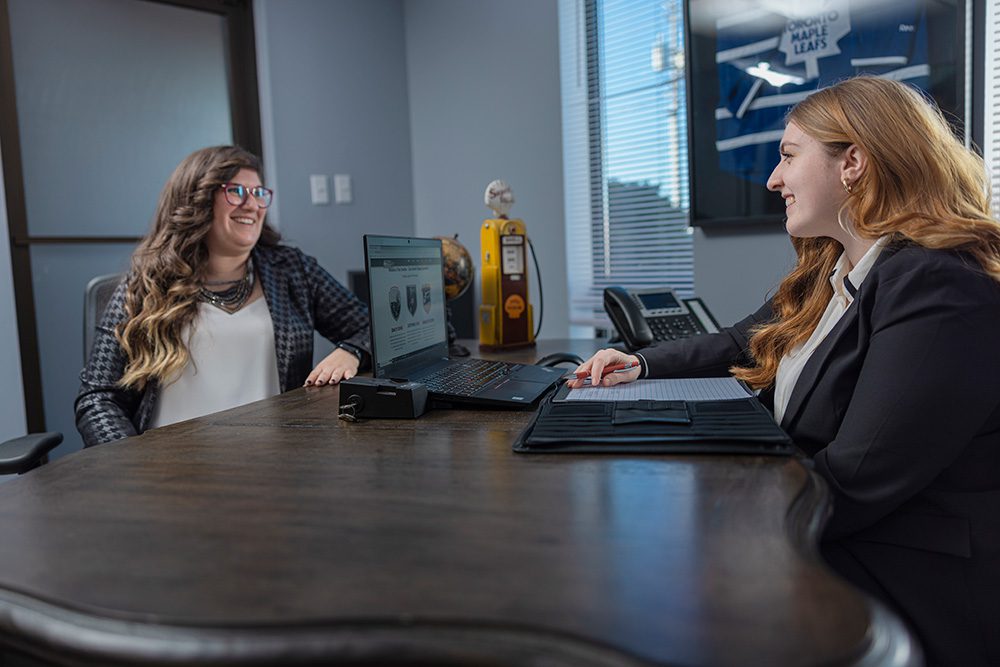 Two female professionals collaborating at computer workstation in modern office