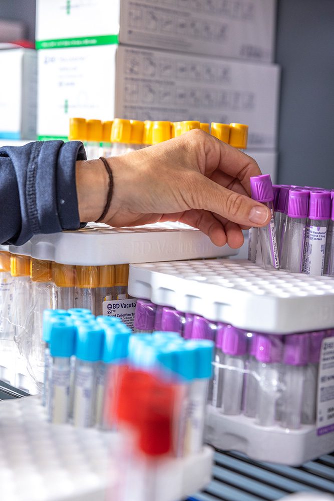 Close-up of hand selecting blood collection tubes for medical testing