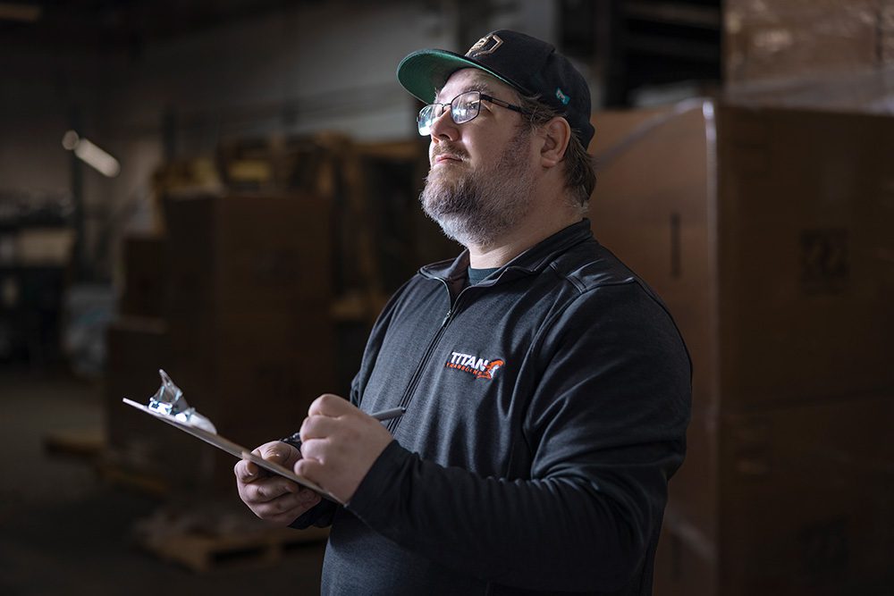 Male warehouse supervisor with clipboard inspecting operations at logistics facility