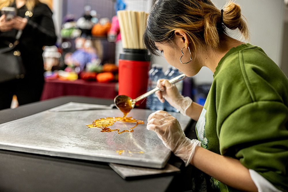 Artist creating sugar art candy on marble slab at festival booth