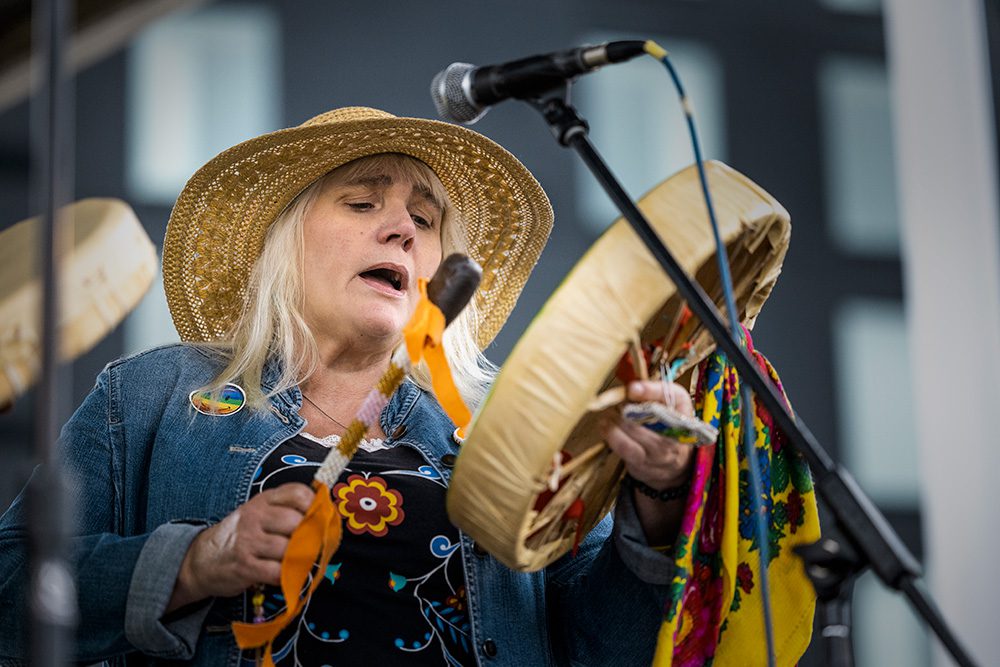 Musician in gold sequined hat playing frame drum and singing