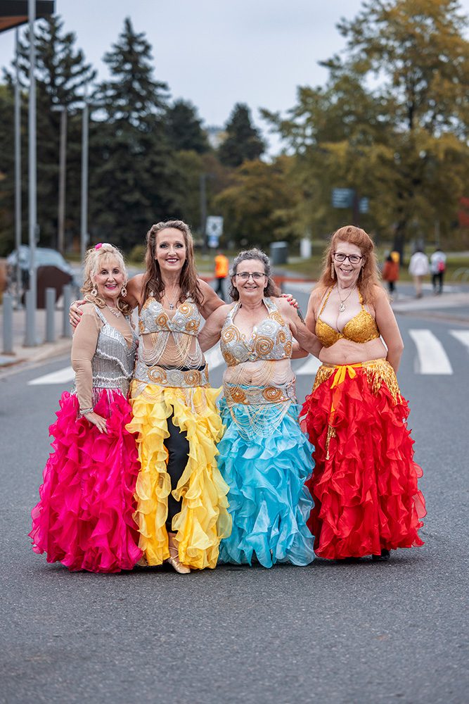 Four belly dancers in colorful ruffled skirts posing at multicultural event