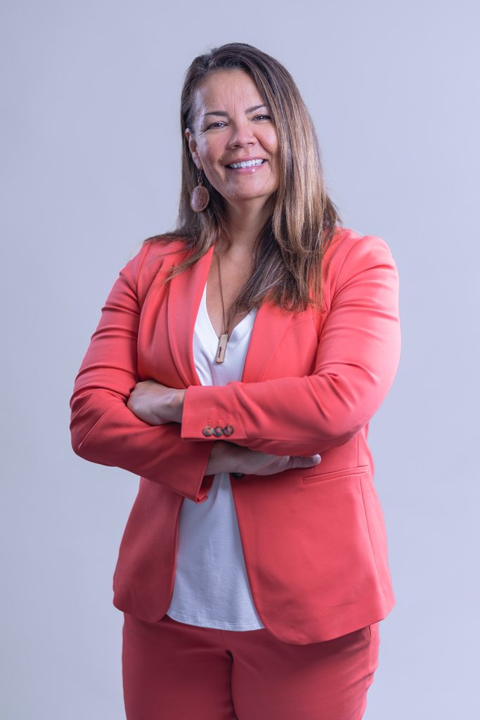 Full body professional portrait of woman in coral pantsuit against light background
