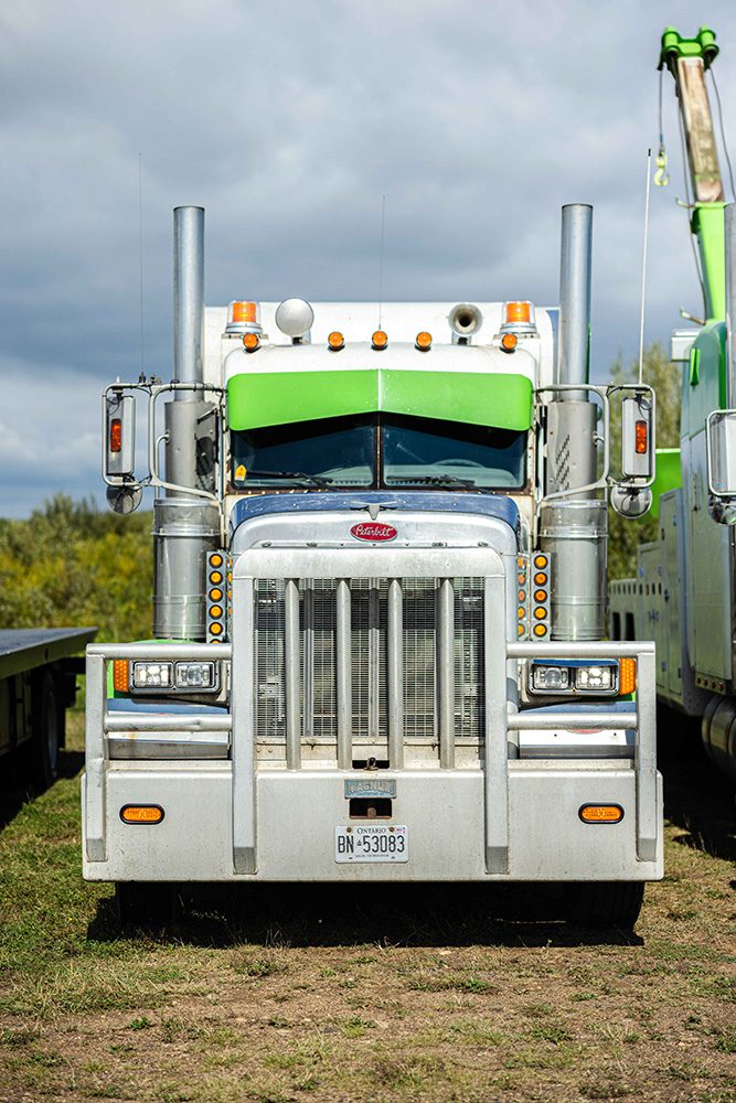 Professional front view photograph of white and green Peterbilt tow truck for commercial trucking photography portfolio