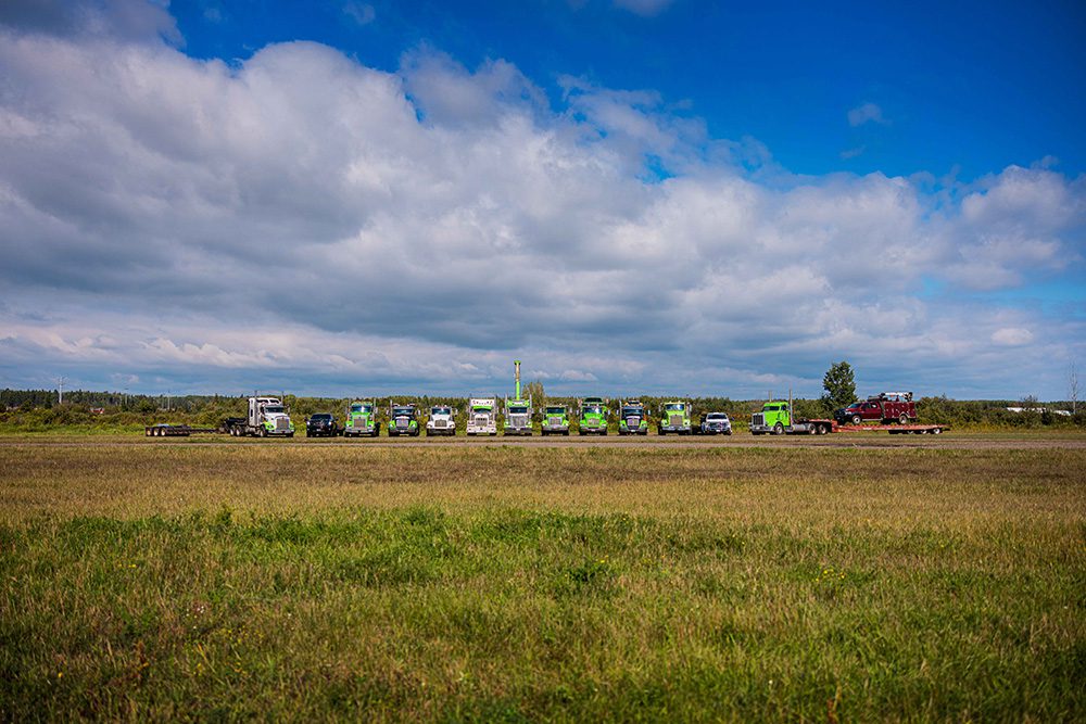 Wide landscape commercial photograph of entire towing fleet under dramatic sky for business marketing materials