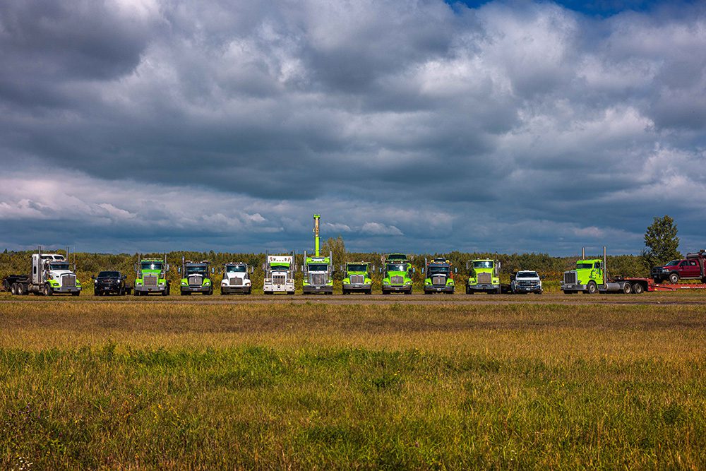 Professional commercial photography of towing truck fleet lined up under dramatic storm clouds for advertising imagery