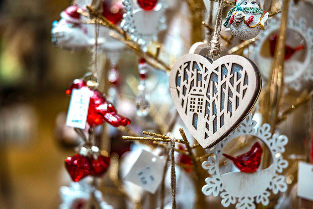 Close-up of Christmas tree ornaments including wooden heart decoration and bird ornament