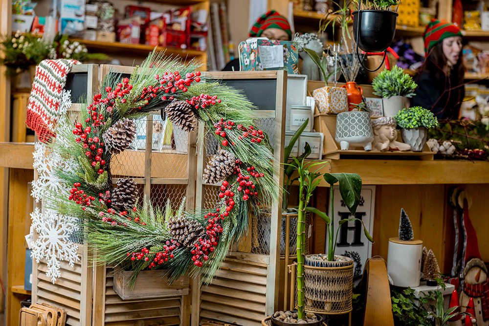 Rustic Christmas wreath with pinecones and red berries displayed against vintage window frame
