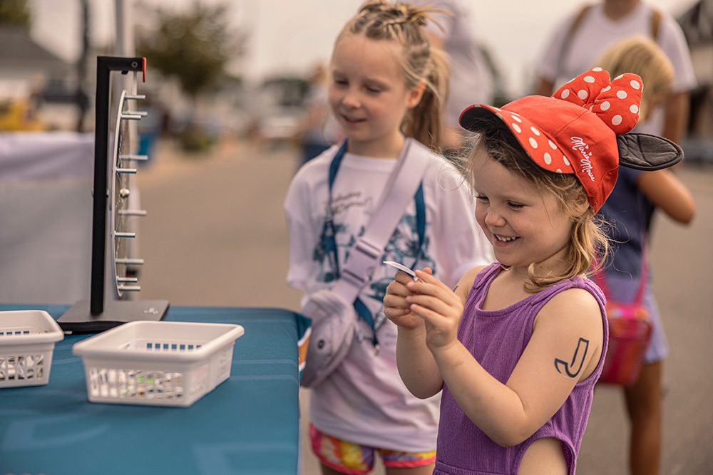 Two young girls interacting with activity booth display at community festival