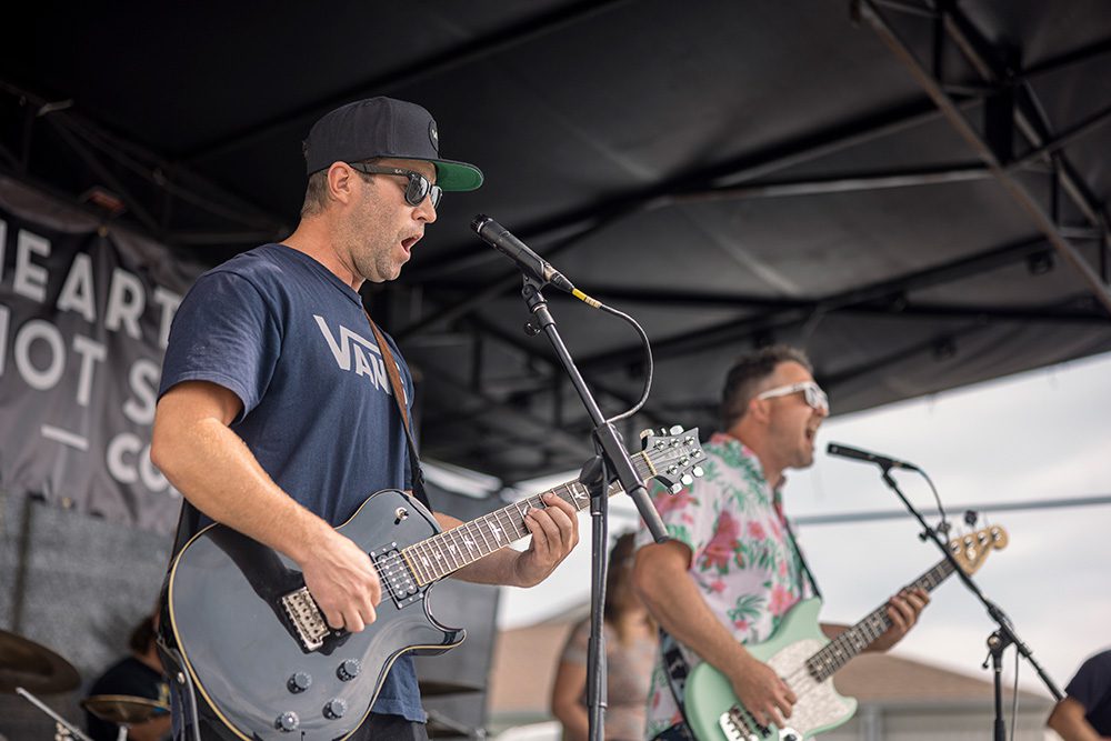 Two guitarists performing on outdoor stage at community street festival