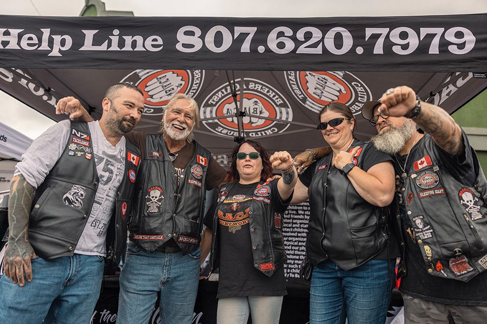 Five members of motorcycle support group posing at their festival booth