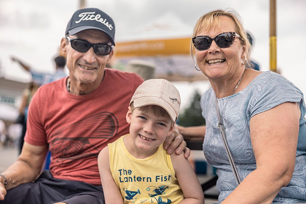 Grandparents and grandson posing together at outdoor community festival