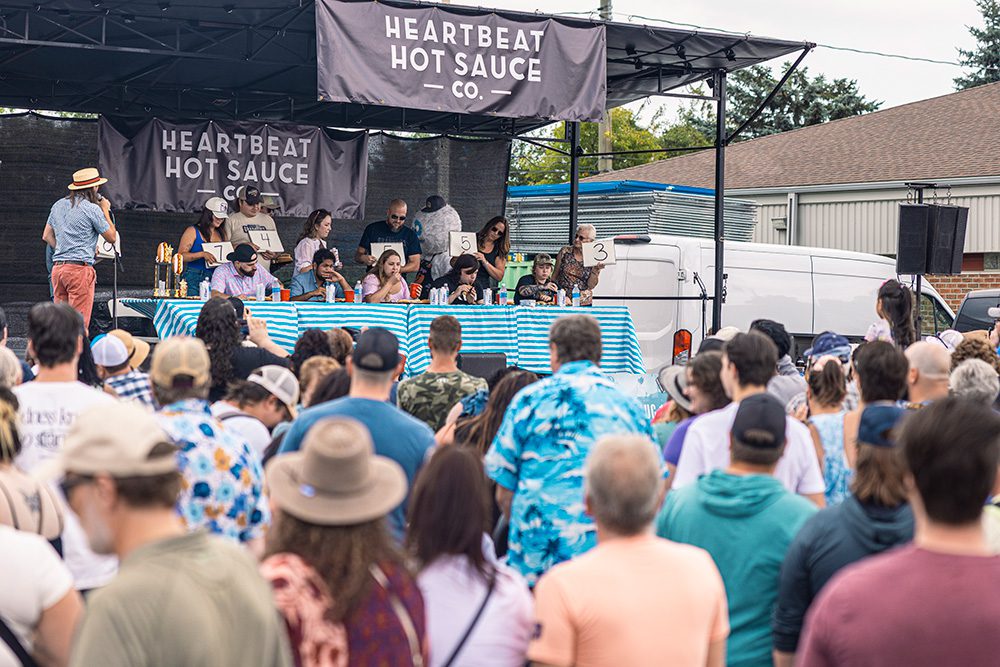 Judges panel at Heartbeat Hot Sauce competition with audience watching at street festival