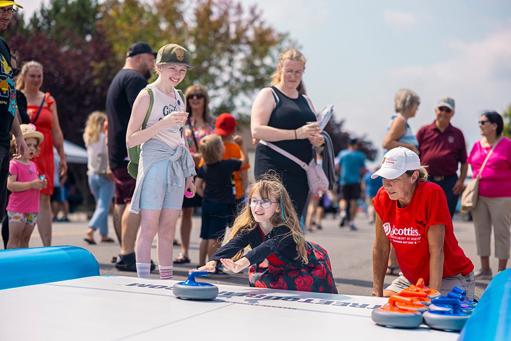 Young girl playing tabletop curling game at community festival activity booth